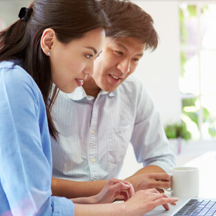 An asian couple looking at their laptop